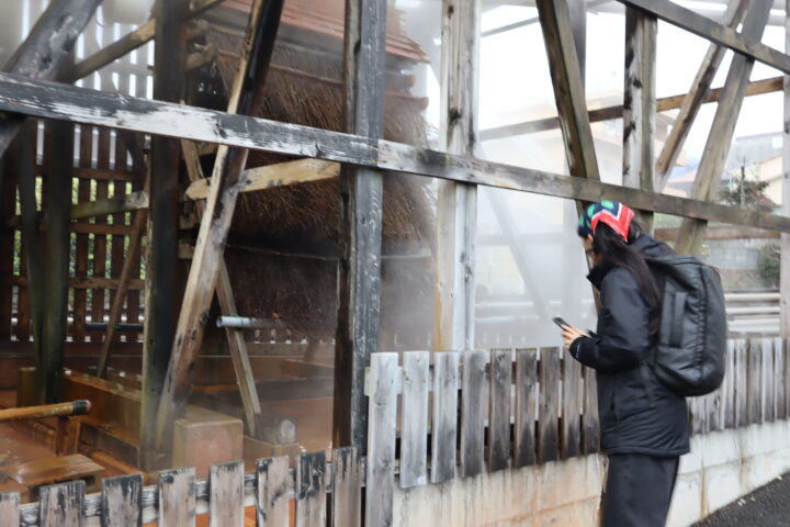 Meitao Qu, the invited residency artist is looking inside a building in Beppu